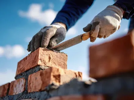Mason laying soft brick in mortar on a Baker neighborhood chimney